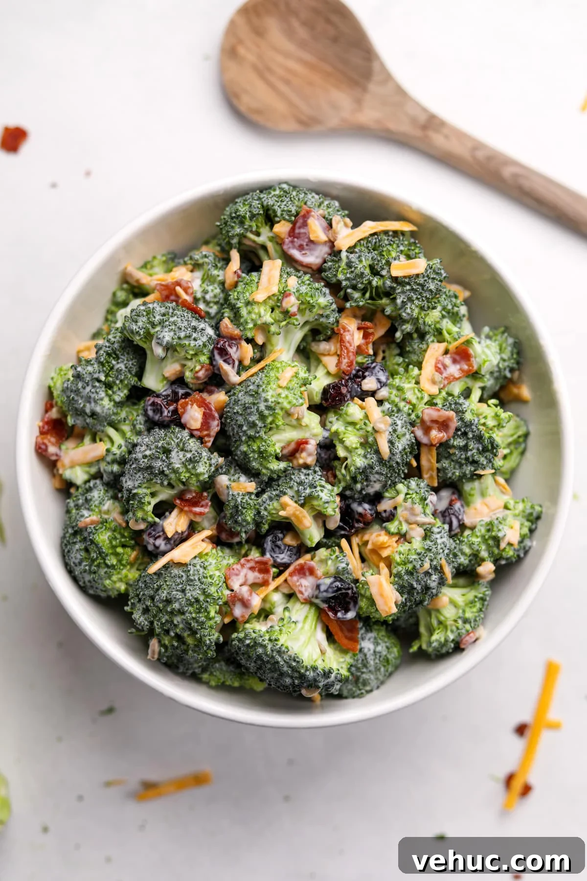 Crispy Broccoli Salad with Creamy Parmesan Dressing 11 A white bowl filled with broccoli salad that's been garnished with bacon and cheddar cheese.