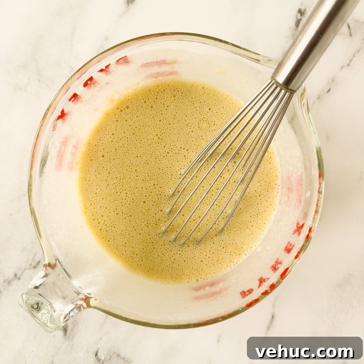 Gluten-Free Dutch Baby Pancake Recipe (German Pancake) 5 Batter for a dutch baby pancake with a whisk in a glass measuring container.