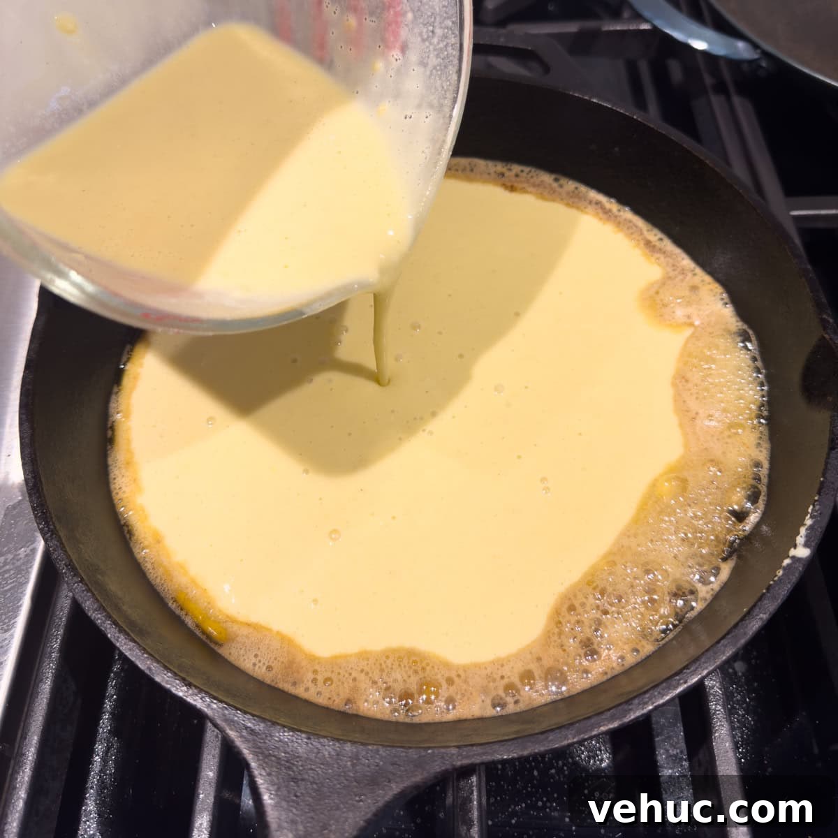 Gluten-Free Dutch Baby Pancake Recipe (German Pancake) 7 Pouring batter for a dutch baby oven pancake into a hot cast iron skillet