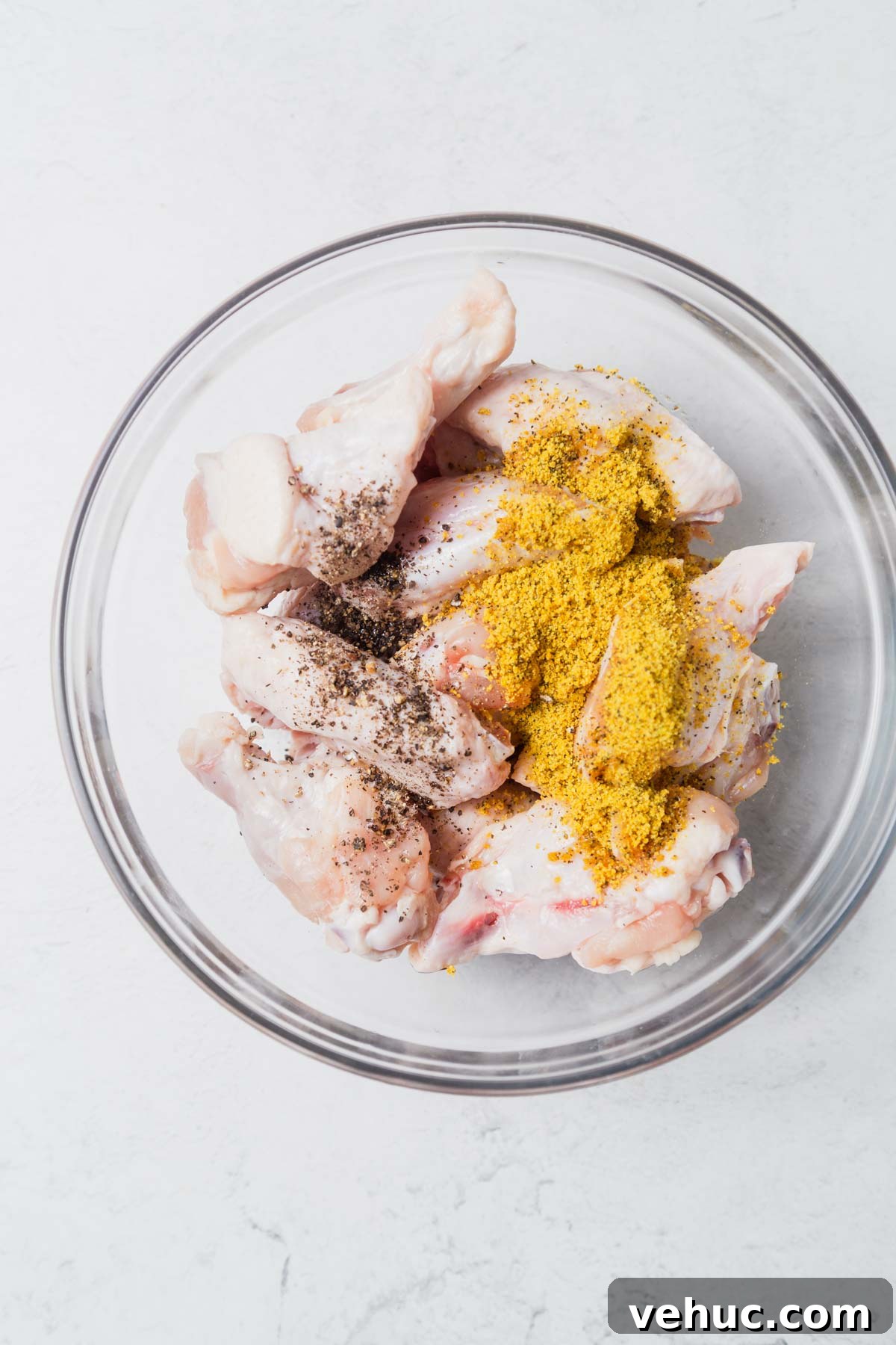 Crispy Lemon Pepper Air Fryer Chicken Wings 4 chicken wings and spices in a bowl for lemon pepper wings.