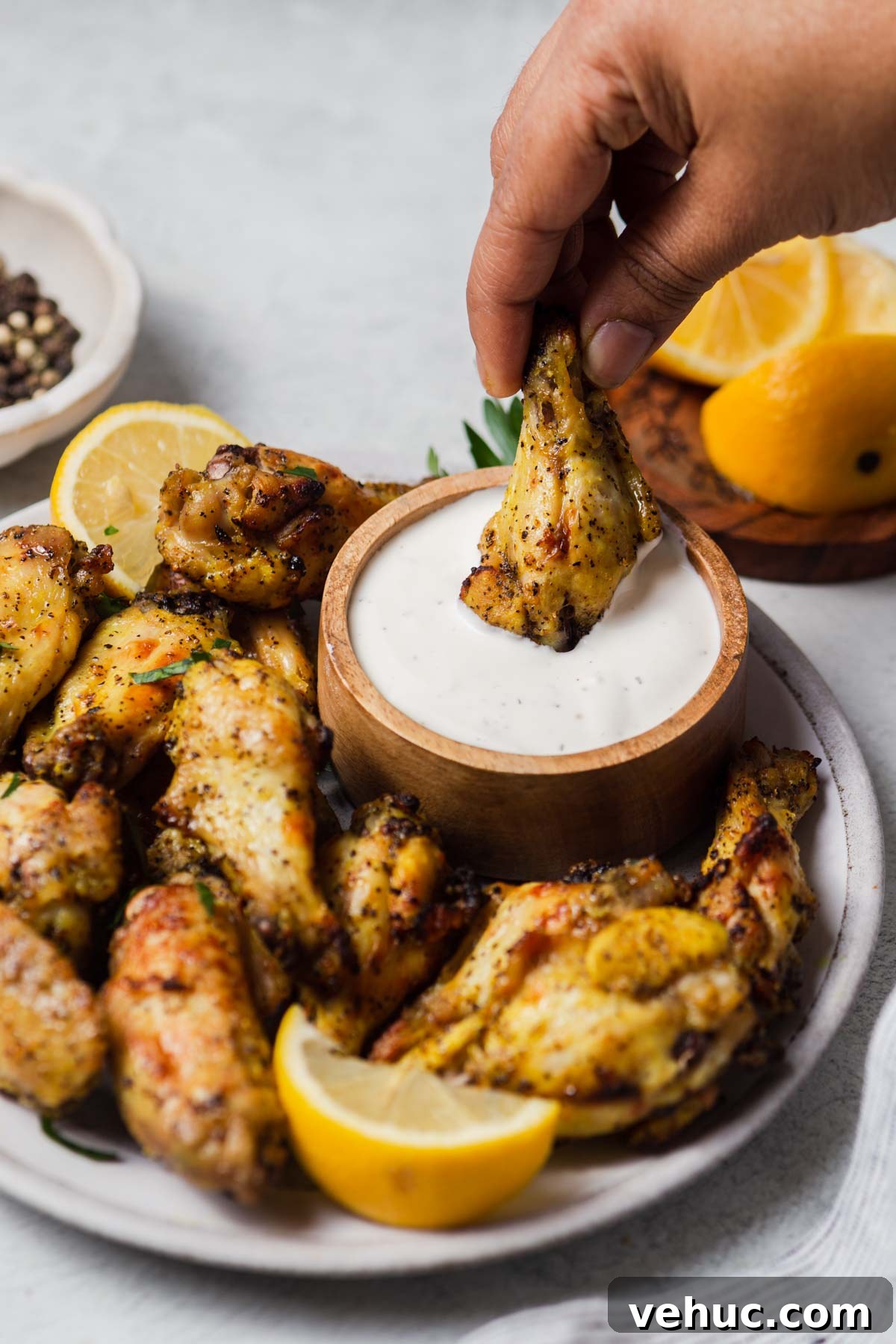 Crispy Lemon Pepper Air Fryer Chicken Wings 8 air fried lemon pepper chicken wing being dipped in a ranch dip.