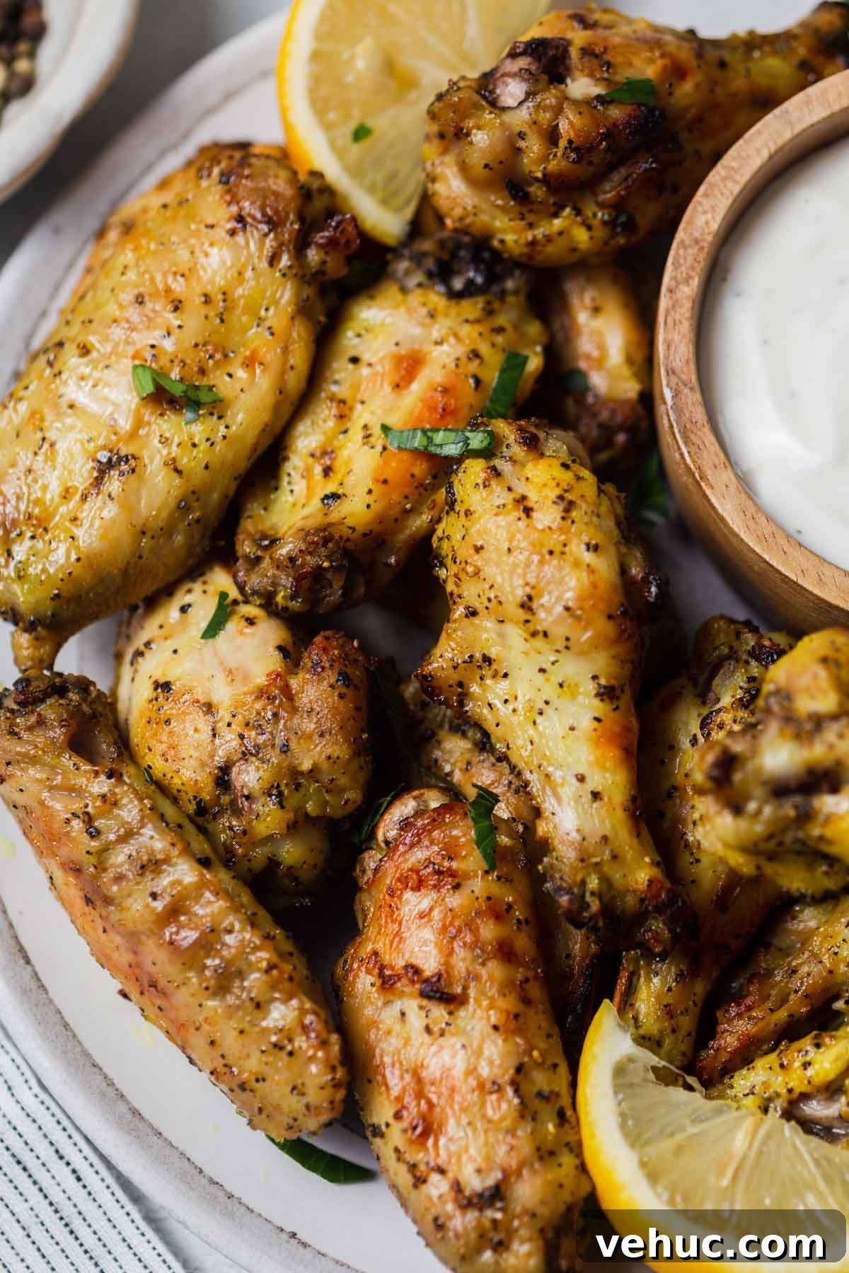Crispy Lemon Pepper Air Fryer Chicken Wings 9 lemon pepper chicken wings in the air fryer with ranch dip on a plate.