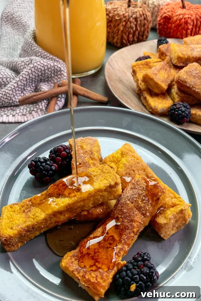 Pumpkin Churro French Toast Sticks Recipe for Fall Brunch 4 Light and fluffy pumpkin French toast sticks with syrup being poured over the top of them on a grey plate.
