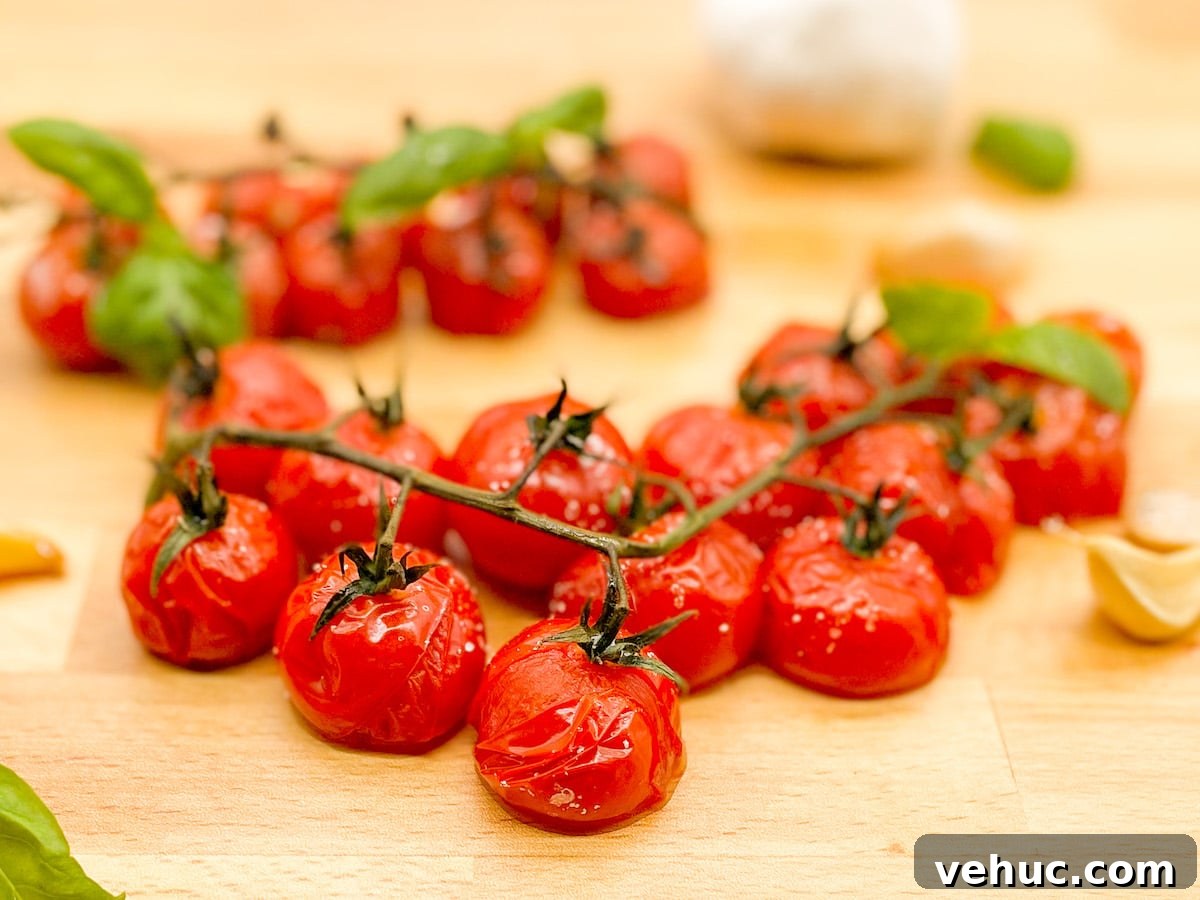 Oven-Roasted Cherry Tomatoes on the Vine: Simple Flavor Boost 2 Roasted cherry tomatoes on the vine with roasted garlic cloves and fresh basil leaves on a wooden butcher block cutting board