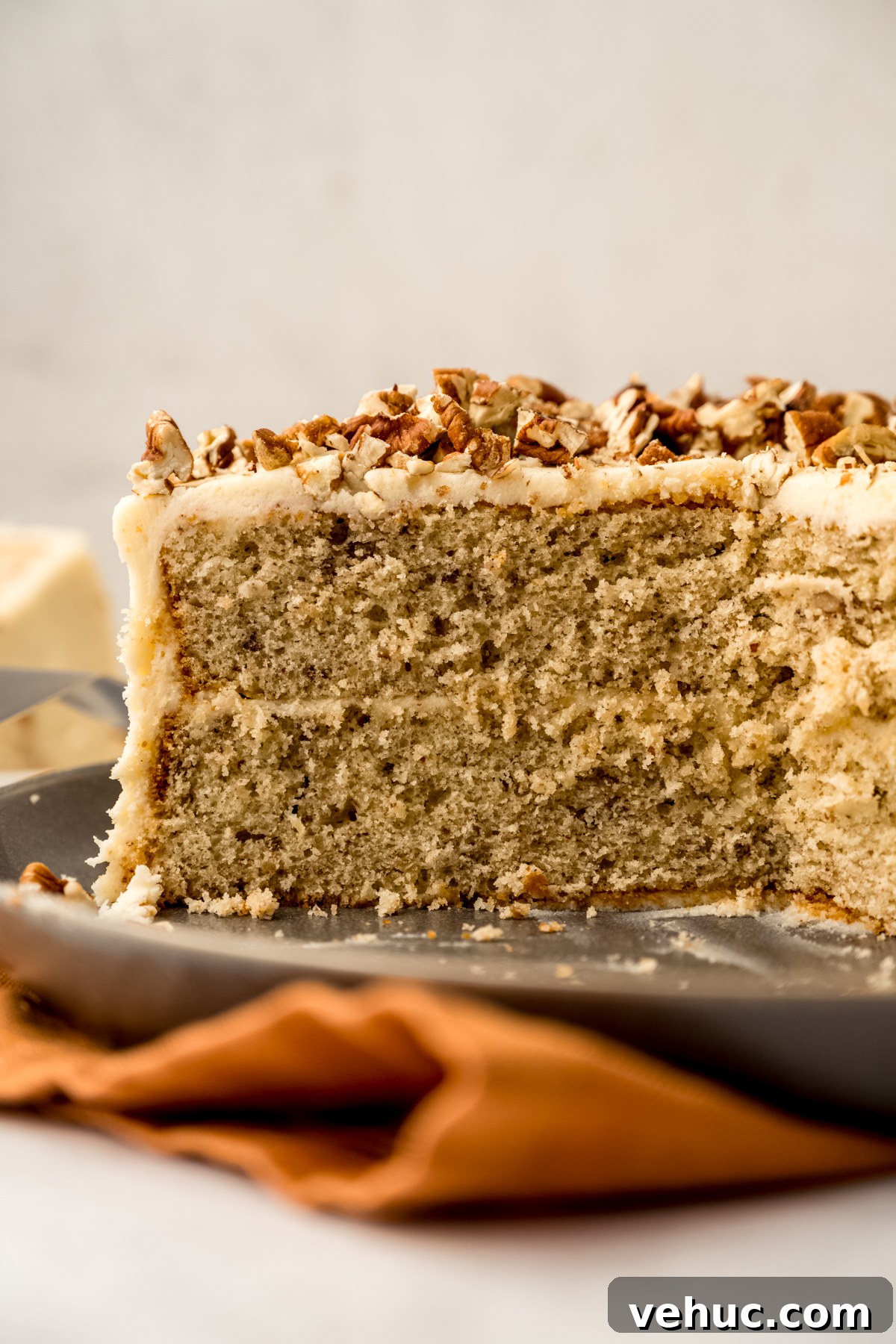 Decadent Butter Pecan Layer Cake Recipe 2 A butter pecan cake on a plate and it has been sliced so you can see the cross section of the cake.