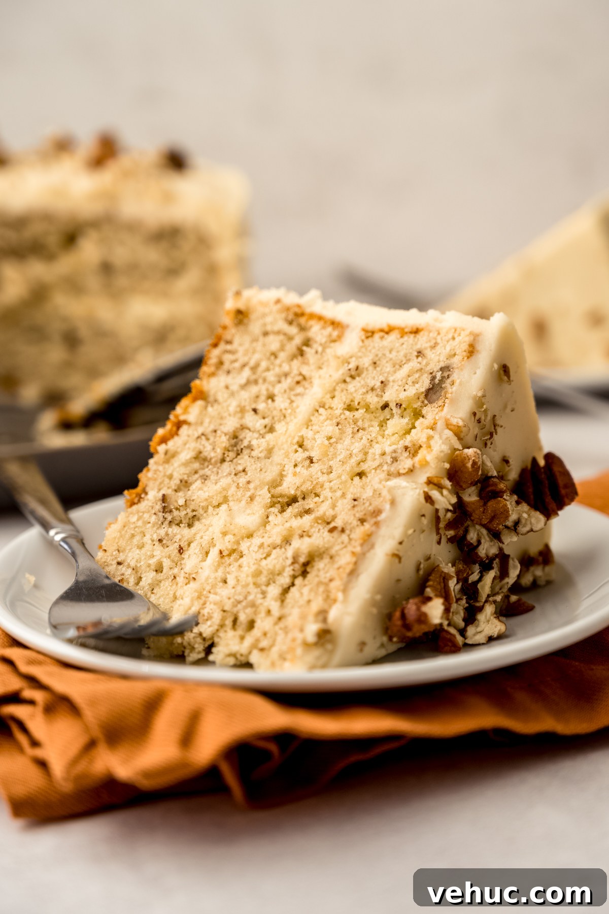 Decadent Butter Pecan Layer Cake Recipe 4 A slice of butter pecan cake on a plate with a fork.