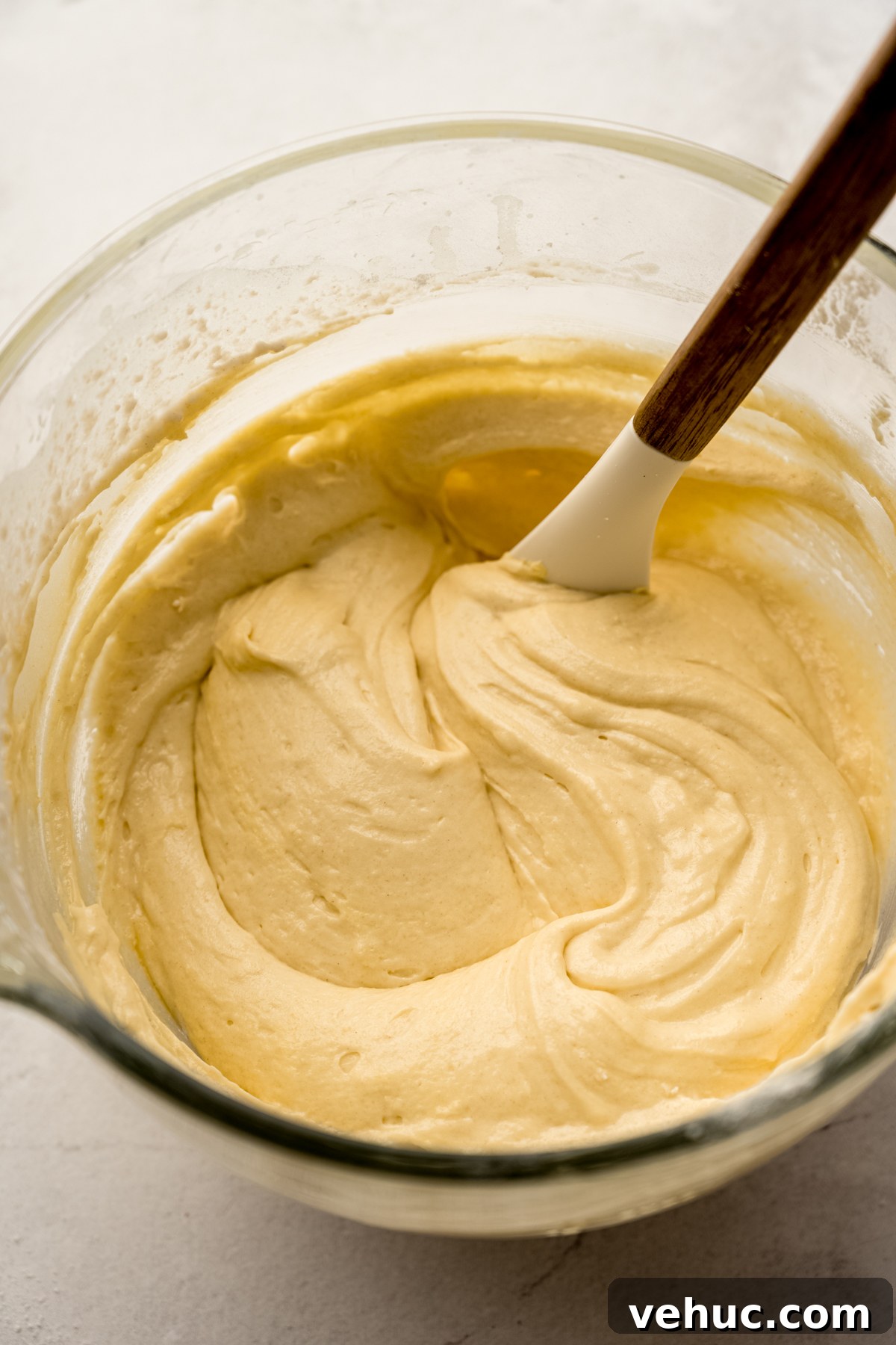 Decadent Butter Pecan Layer Cake Recipe 6 The batter for butter pecan cake in the bowl of a stand mixer with a spatula in it.