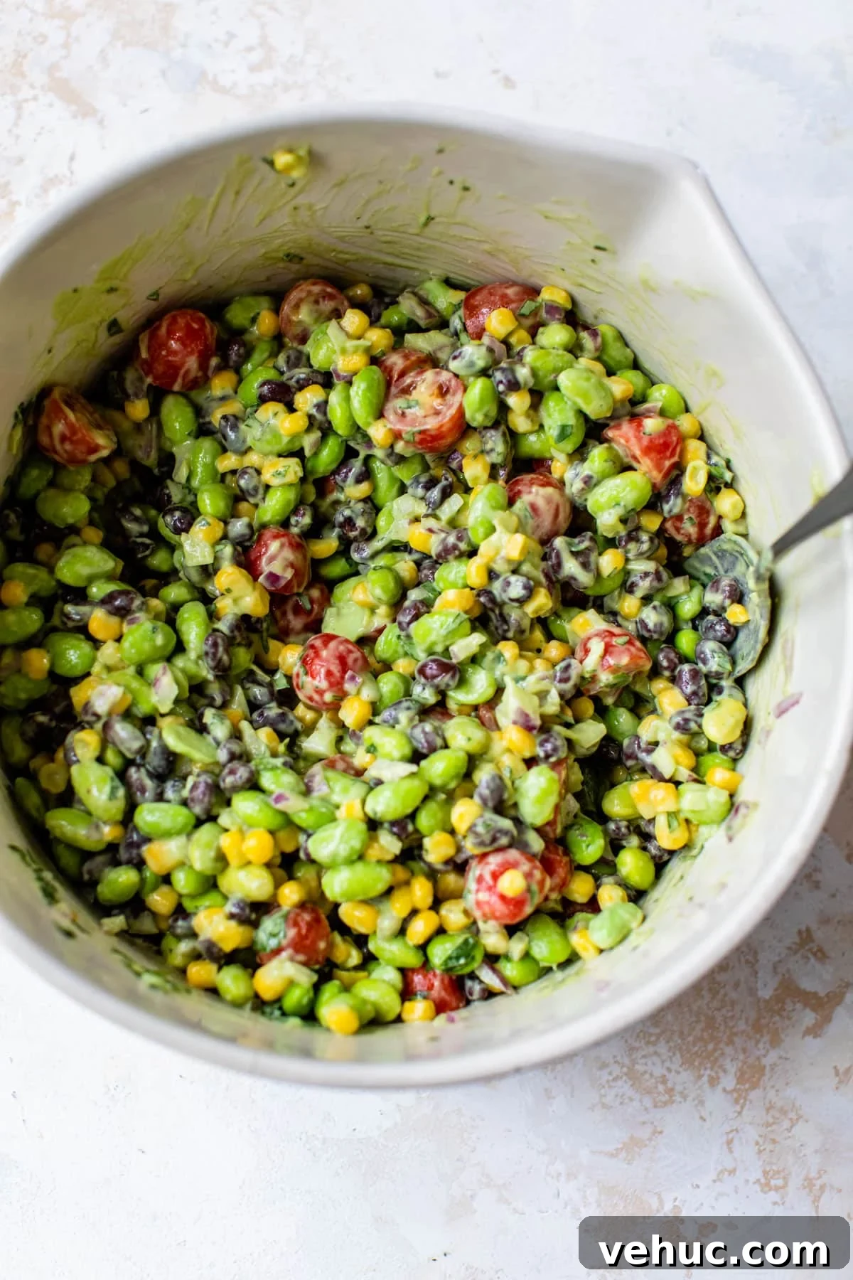 Citrus Edamame Salad with Avocado and Sesame Dressing 5 edamame salad just mixed together in a large bowl with a spoon