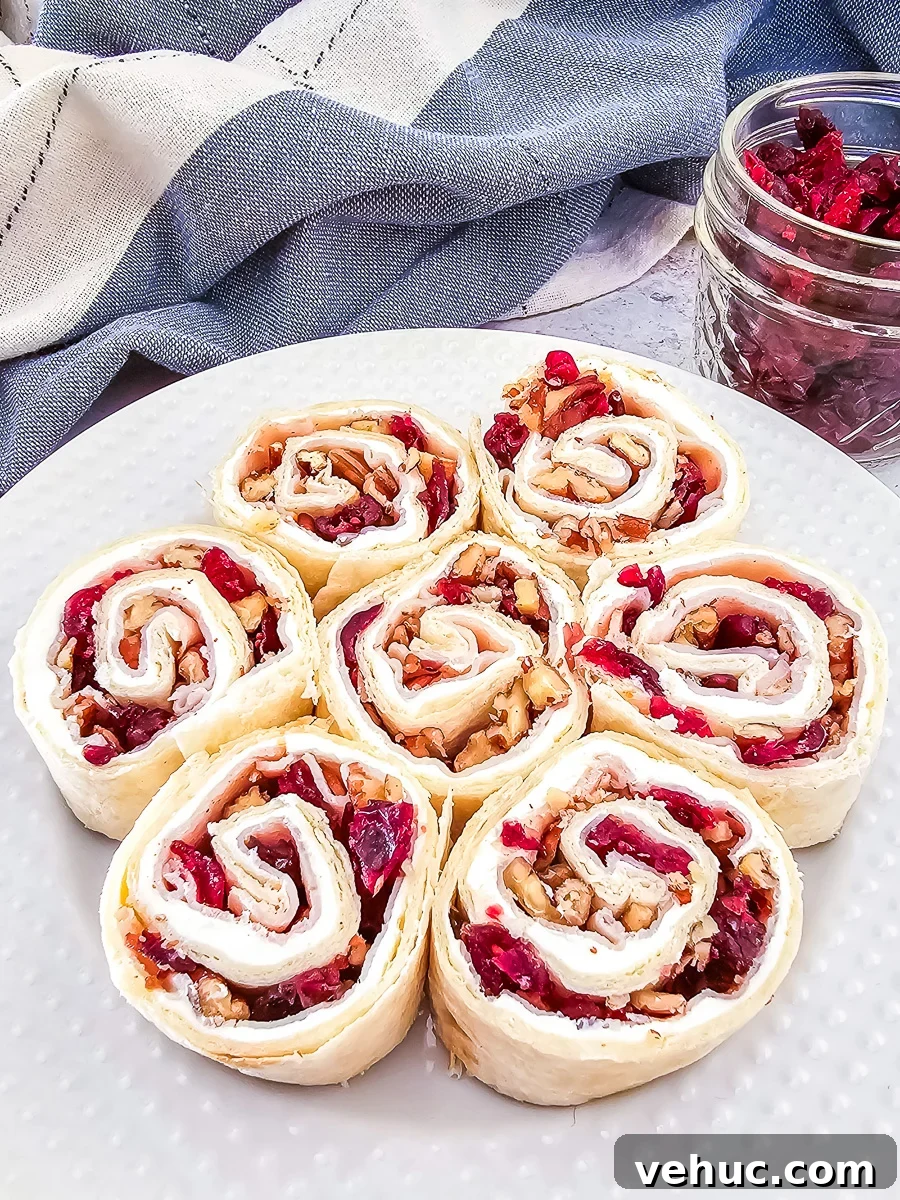 Christmas Brunch Finger Foods to Impress Guests 7 Cranberry and turkey pinwheels on a white serving plate for a holiday party.