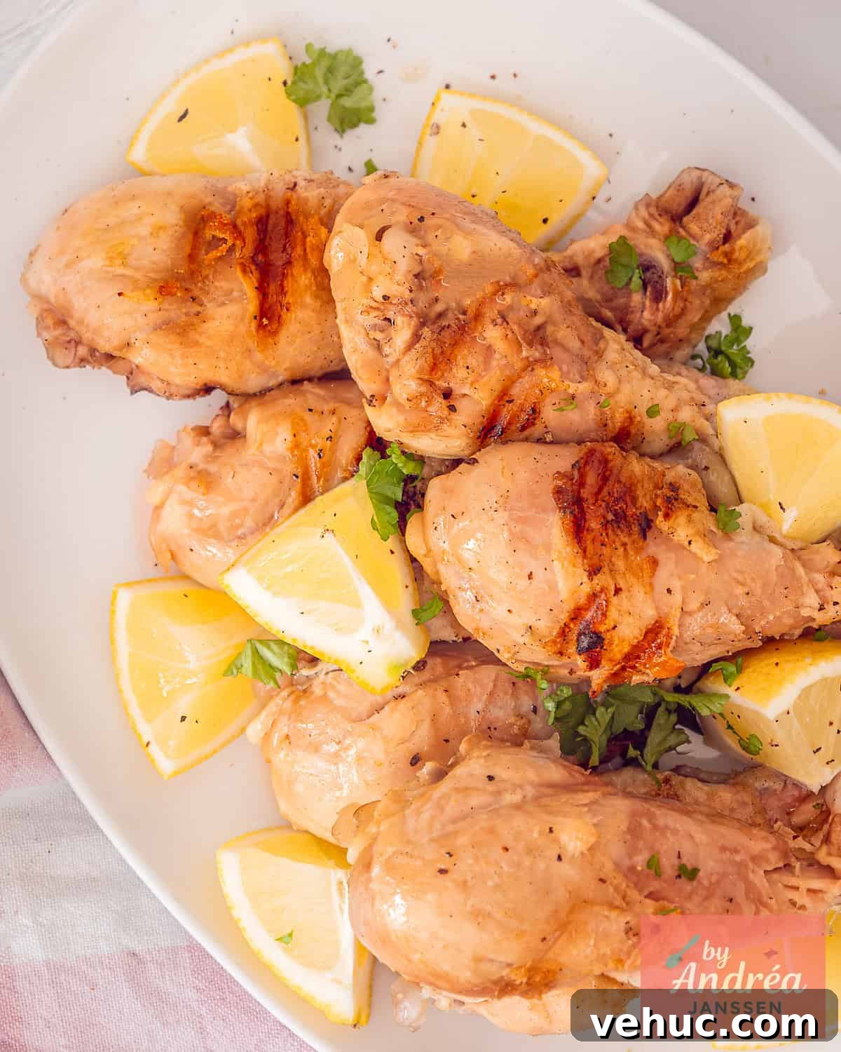 Citrus-Brined Chicken Drumsticks with Gin Marinade 2 A photo from above with grilled and brined drumsticks on a white platter surrounded by lemon.