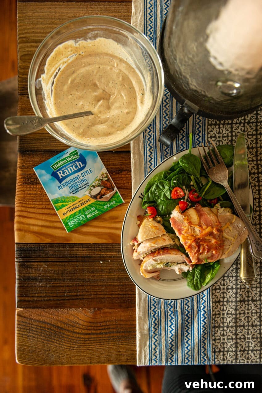 Flat lay shot over a bowl of ranch salad dressing and plated sliced bacon wrapped chicken breast