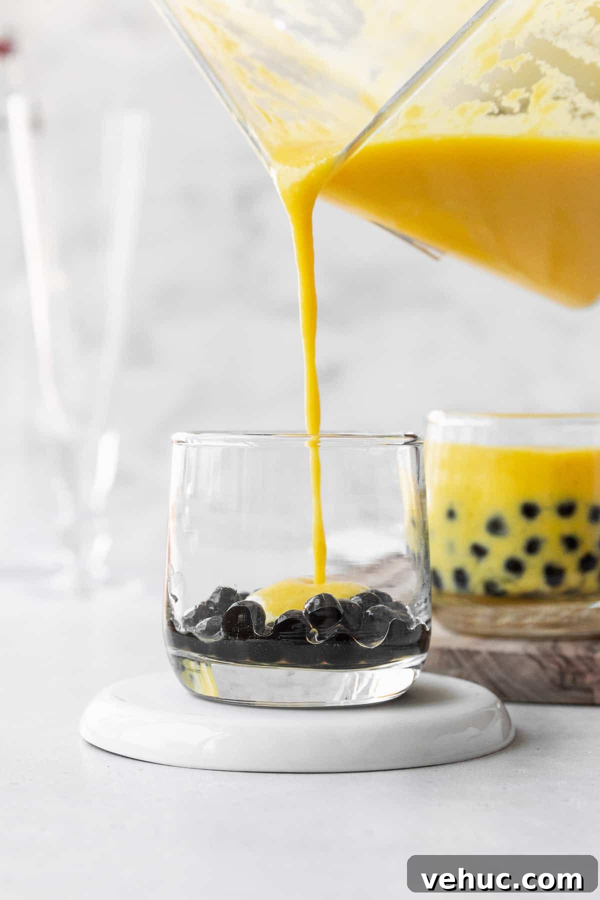 Mango Bubble Tea: Refreshing Homemade Boba Recipe 11 Pouring the mango puree into a small glass with the boba pearls.