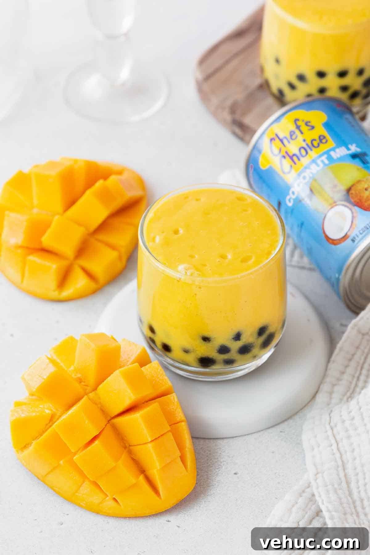 Mango Bubble Tea: Refreshing Homemade Boba Recipe 13 A small glass of the mango boba tea next to a can of chef's choice coconut milk and a cubed mango.