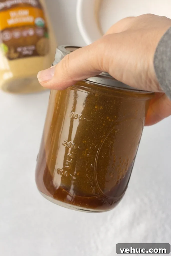 A brown chicken marinade being shaken in a closed mason jar.