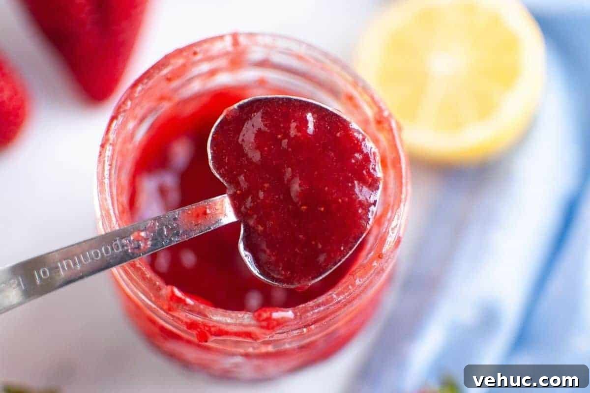 11 Strawberry Recipes That Highlight Their Sweet-Tart Flavor 11 A heart-shaped measuring spoon holds a scoop of vibrant red strawberry puree over a glass jar filled with more puree, surrounded by fresh strawberries and a lemon half.