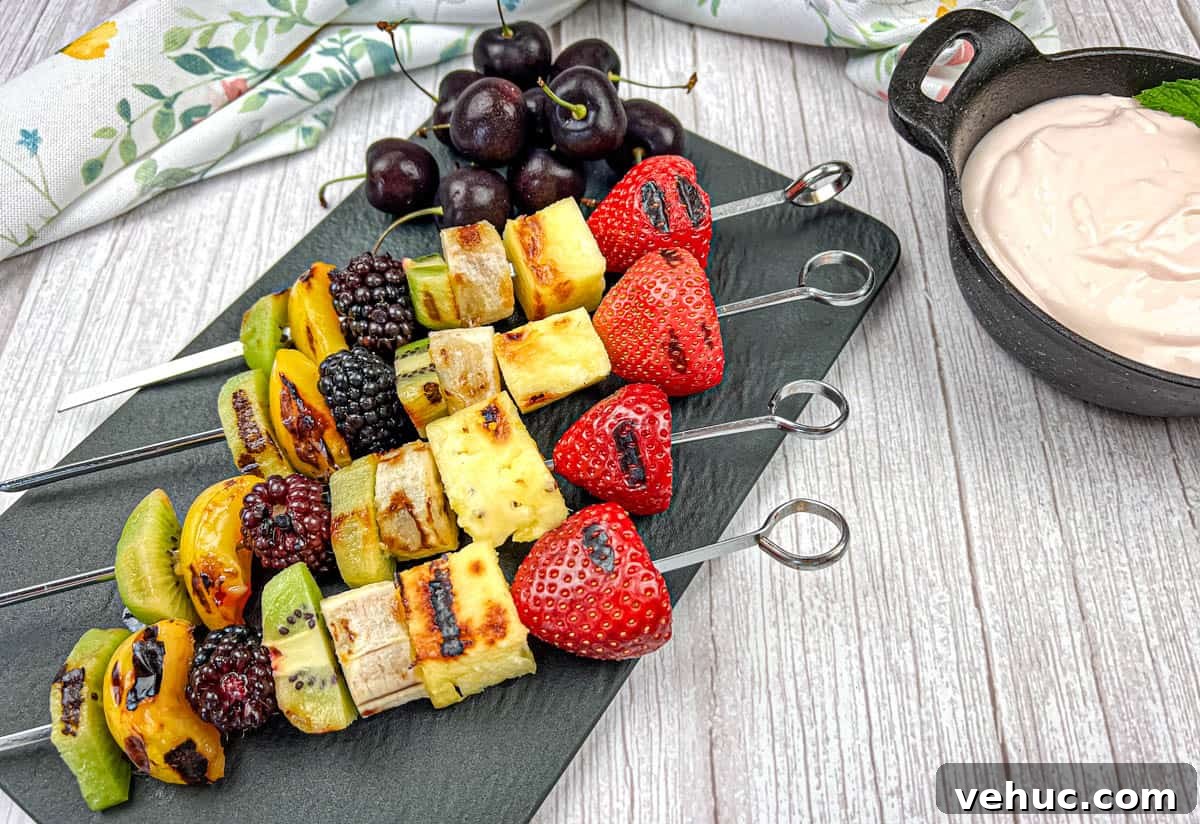 11 Strawberry Recipes That Highlight Their Sweet-Tart Flavor 12 Four pieces of grilled fruit skewers on a slate plate with a bowl of cherry dip.