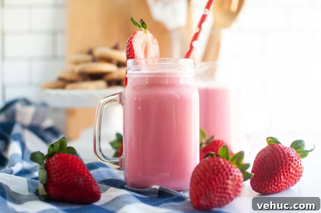 11 Strawberry Recipes That Highlight Their Sweet-Tart Flavor 8 Two pink strawberry milk in glass jars with straws and strawberry garnishes, on a blue and white checkered cloth.