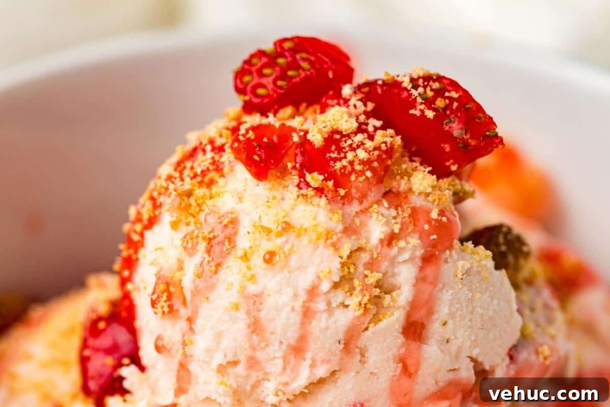 11 Strawberry Recipes That Highlight Their Sweet-Tart Flavor 9 Close-up of a bowl of ice cream topped with crushed cookies, strawberry pieces, and a drizzle of strawberry sauce.