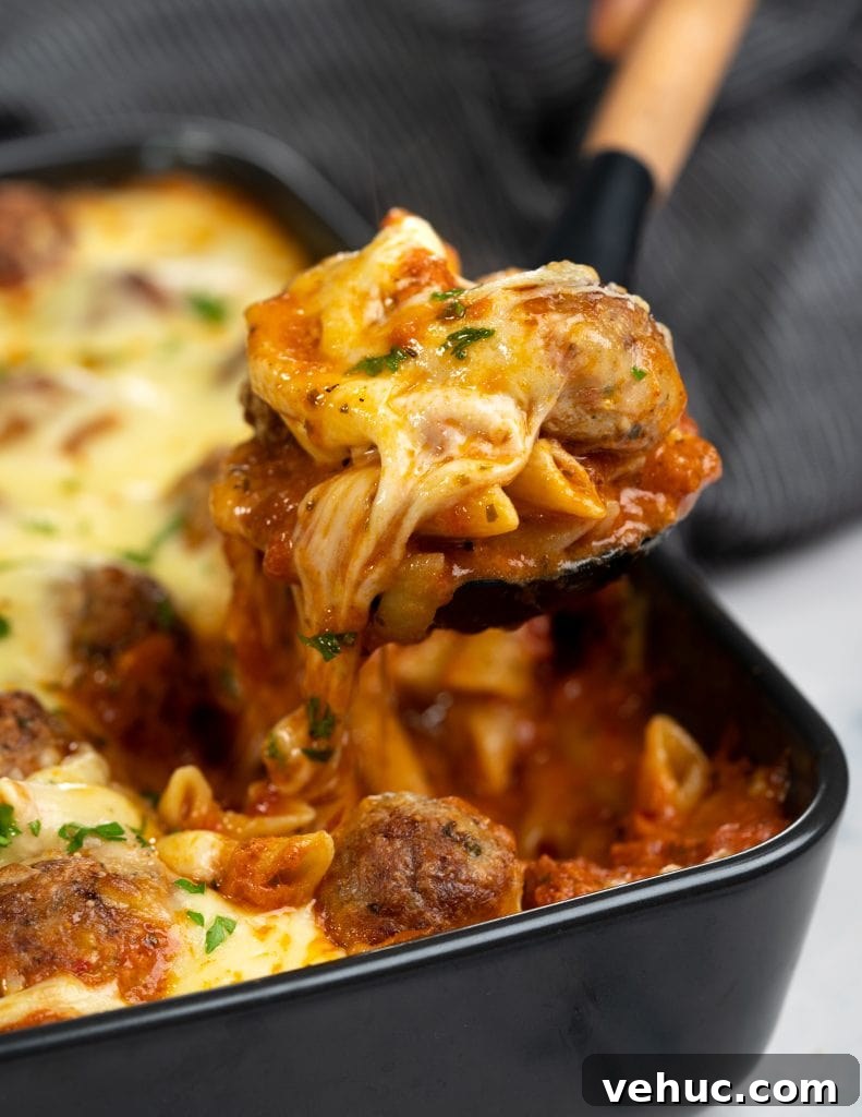 Creamy Chicken and Zucchini Casserole for Weeknight Dinner 9 Slice of meatball casserole picked with a spatula showing strands of cheese and saucy pasta along with chunks of tender meatball
