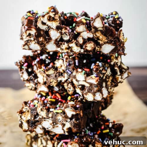side view of stack of Ultimate Popcorn Rocky Road bars on baking parchment on wooden board