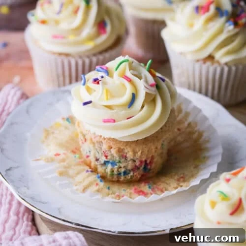 Gluten-Free Funfetti Cupcake on a plate with the liner removed showing the soft tender fluffy crumb