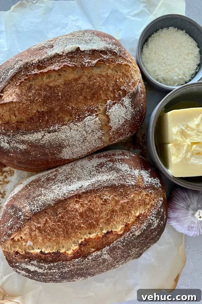Irresistible Sourdough Garlic Bread Recipe You’ll Crave 3 2 small sourdough loaves pictured with a head of garlic, bowl of butter and bowl of parmesan cheese.