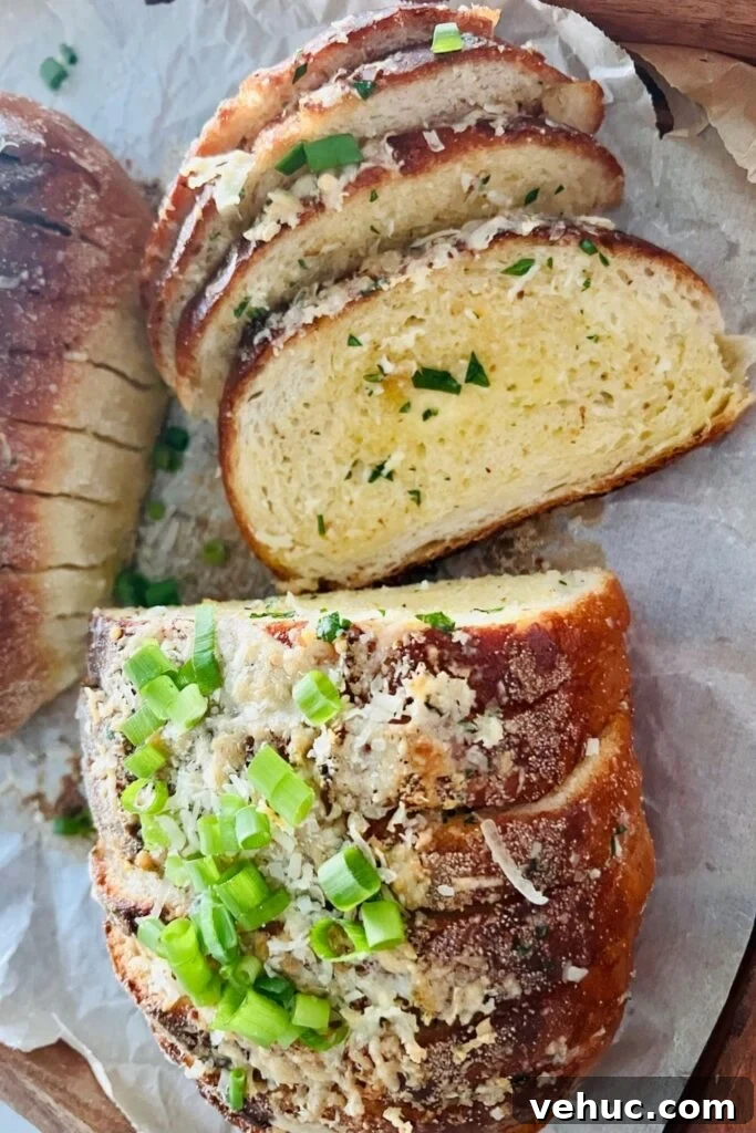 Irresistible Sourdough Garlic Bread Recipe You’ll Crave 6 Sourdough garlic bread topped with parmesan and chives. There is piece laying open so you can see the melted butter and parsley inside.