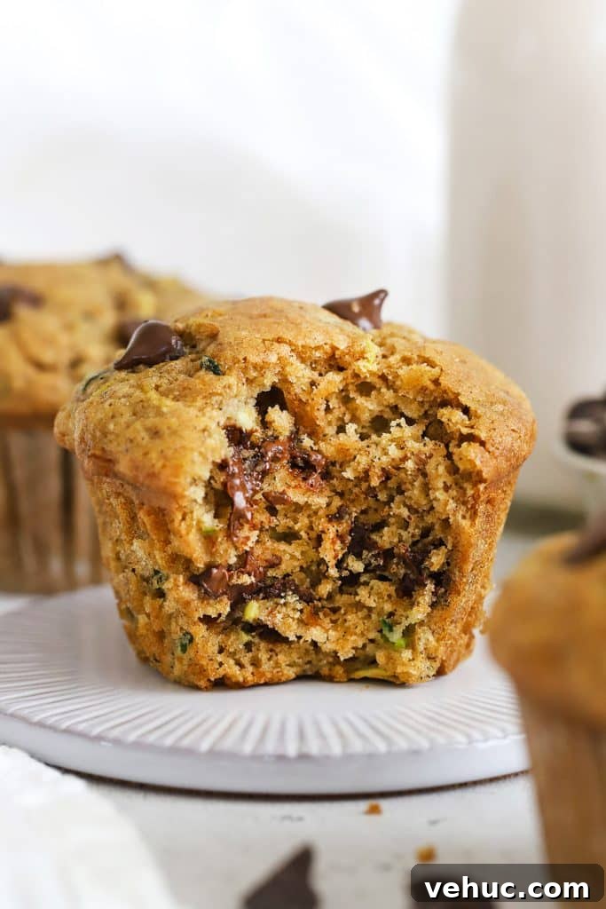 Gluten-Free Zucchini Cake with Brown Butter Cream Cheese Frosting 12 Front view of a gluten-free chocolate chip zucchini muffin with a bite out of it, revealing how moist and fluffy it is inside