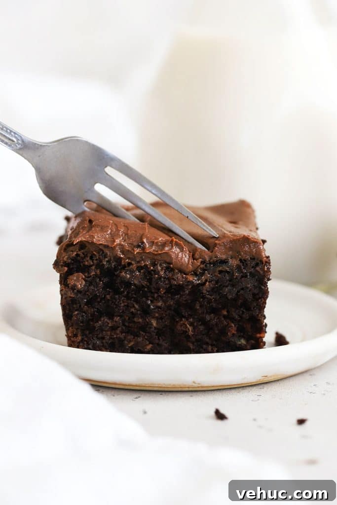 Gluten-Free Zucchini Cake with Brown Butter Cream Cheese Frosting 10 a fork cutting into a slice of gluten-free chocolate zucchini cake with chocolate frosting