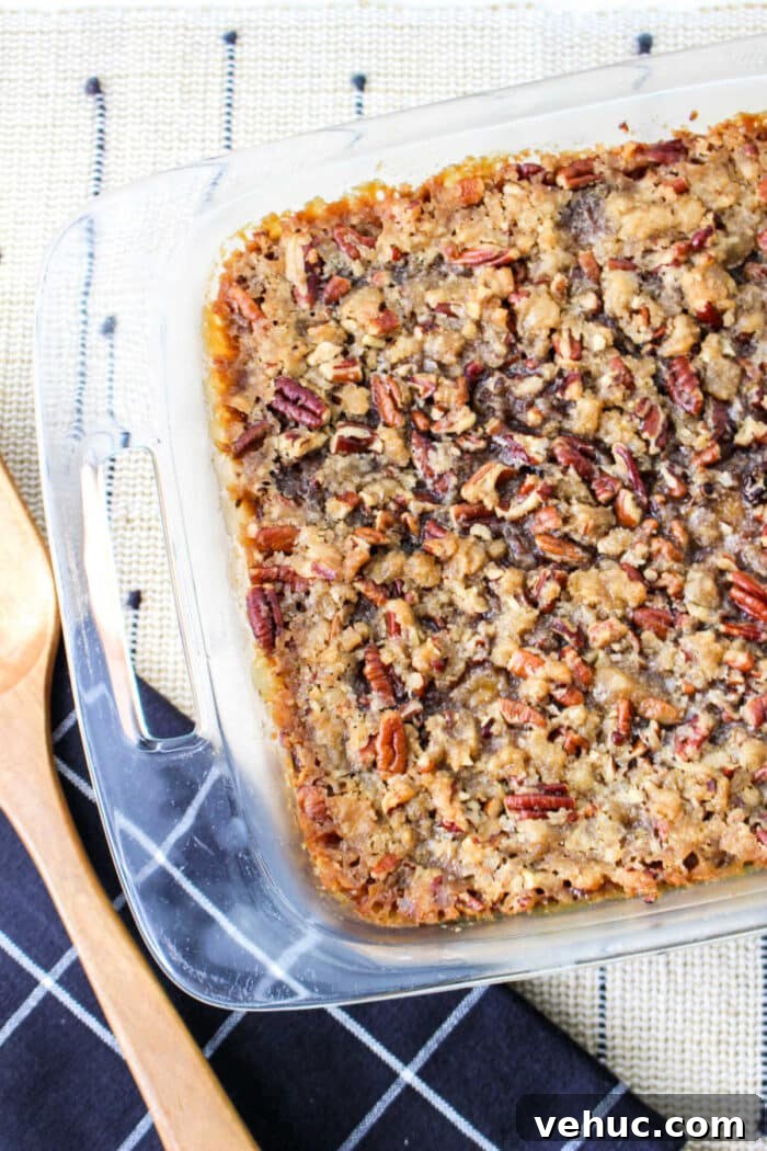 Creamy Sweet Potato Casserole Using Canned Yams 6 A glass baking dish with a freshly baked sweet potato casserole with canned yams, accompanied by rustic wooden cooking utensils.