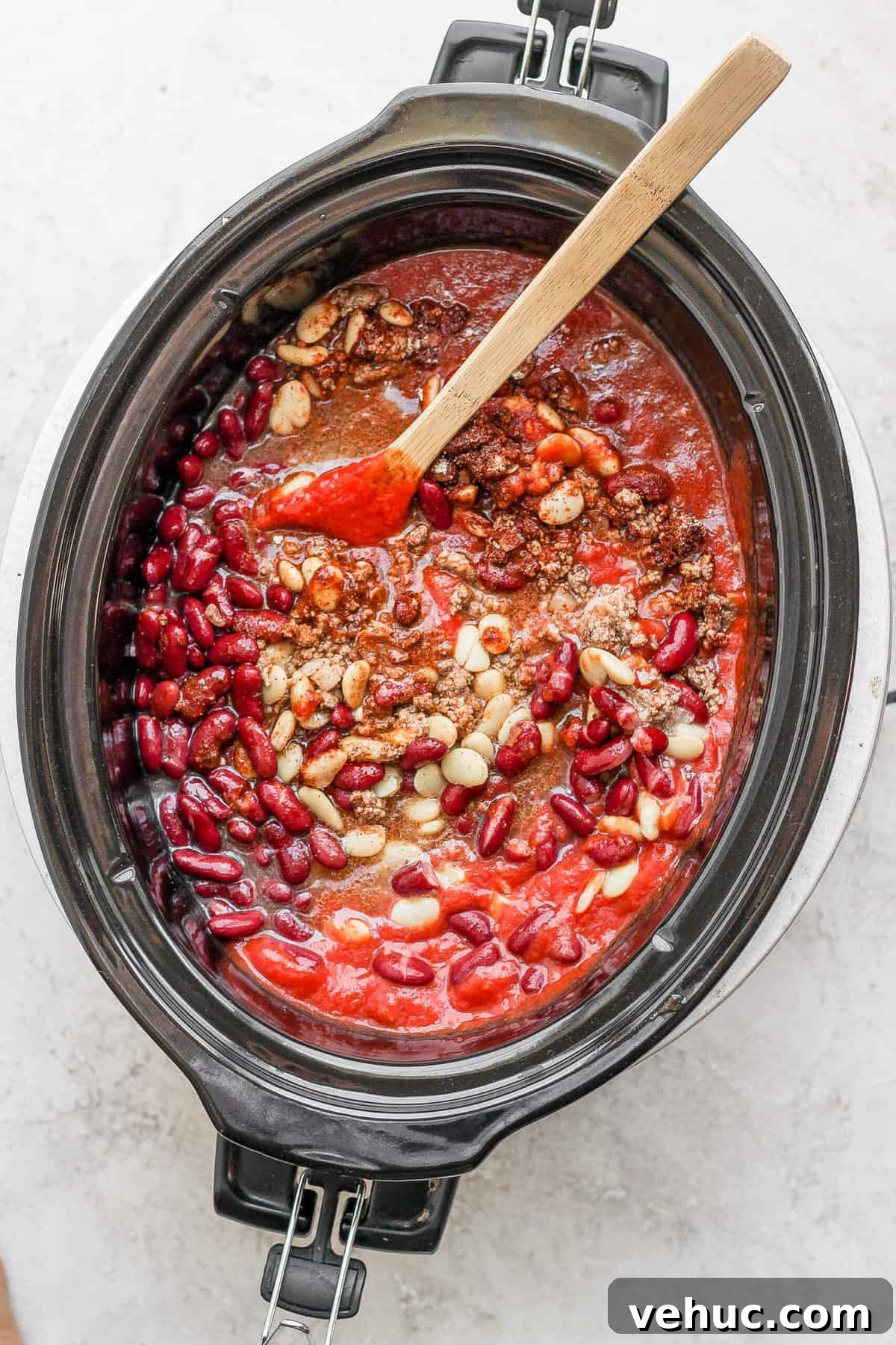 Slow cooker chili in a crock pot with a wooden spoon.