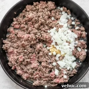 Ground beef and onions cooked in a skillet with flavorful slow cooker chili spices.