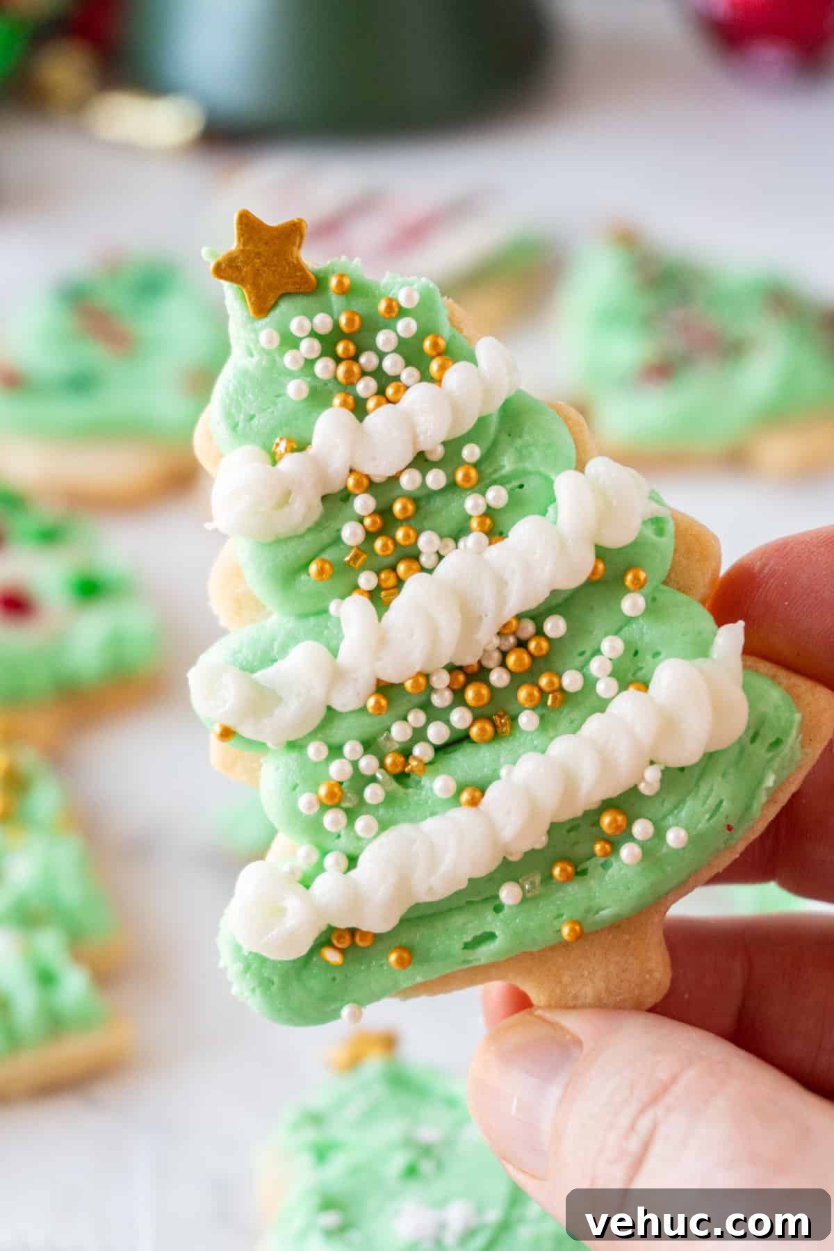 Christmas Tree Cookie Recipes: Festive Holiday Treat Ideas 5 holding Christmas Tree Cookie with green and white frosting
