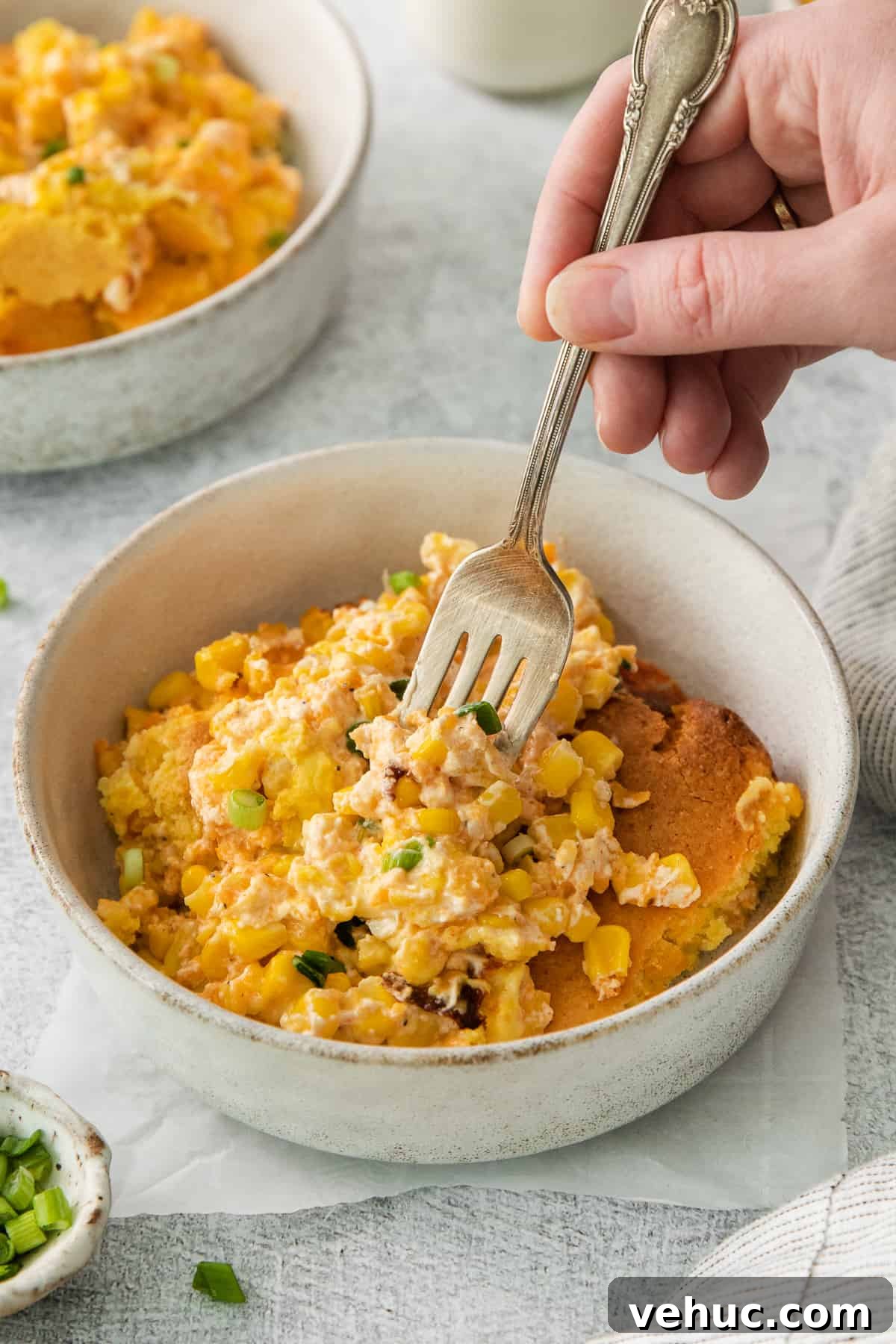 Creamy Cheddar Corn Casserole Recipe for Comforting Sides 7 a person holding a fork in a bowl of food.