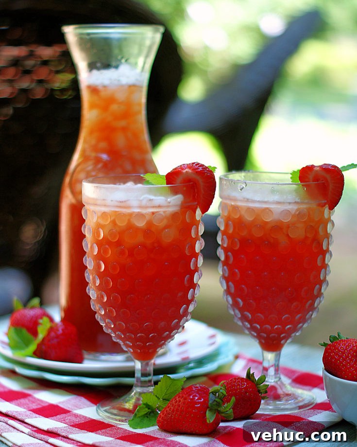 A carafe and 2 glasses of strawberry tea on the patio.