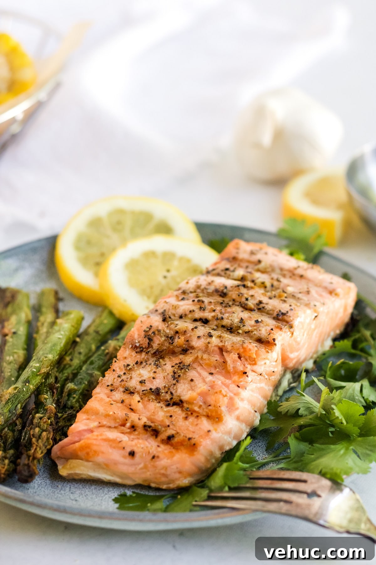 Grilled salmon on a grey plate with herbs and sliced lemons. 