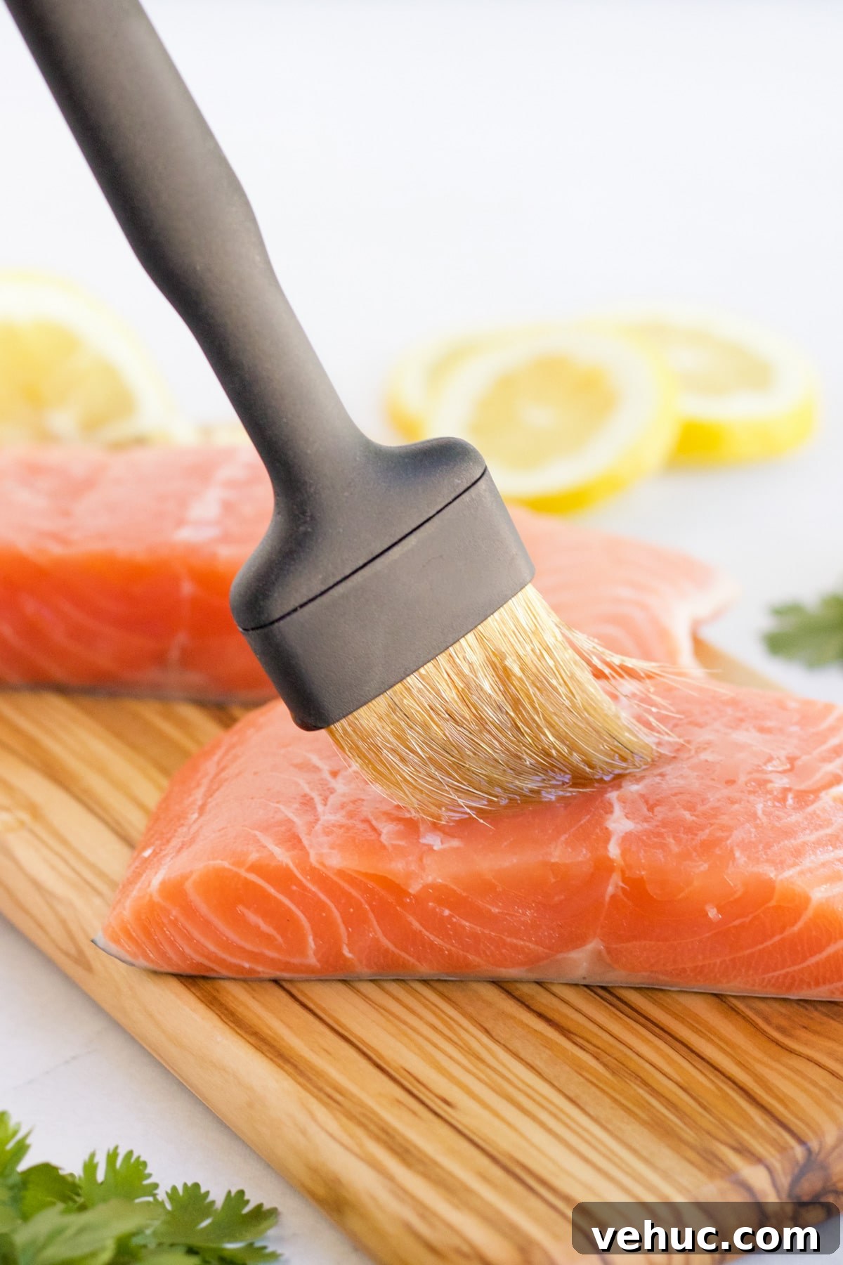 Salmon being prepared for the grill by brushing olive oil on it.