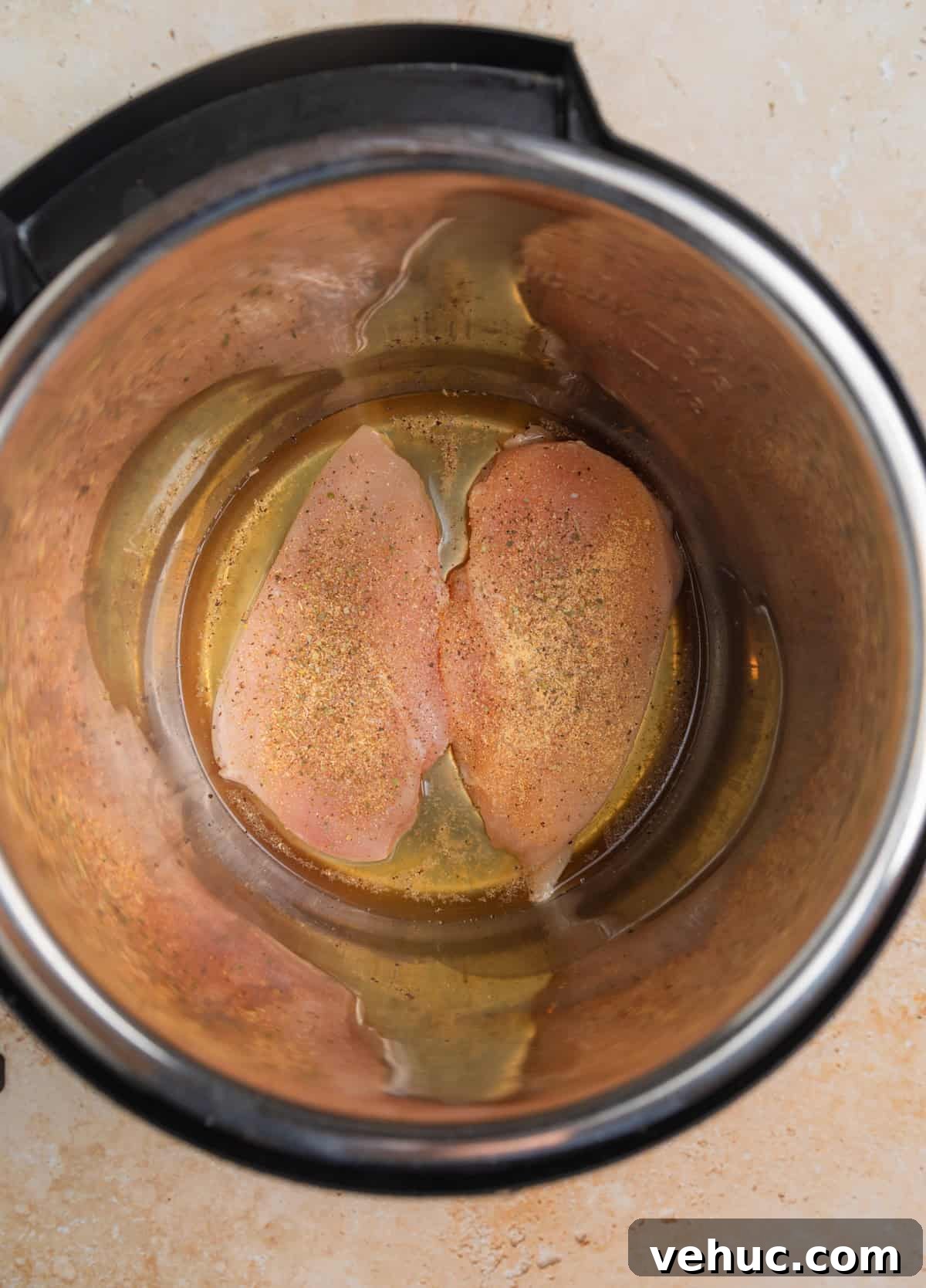 Creamy Parmesan Chicken in the Instant Pot: Quick Weeknight Meal 4 Chicken breast seasoned and placed in pressure cooker pot with broth.