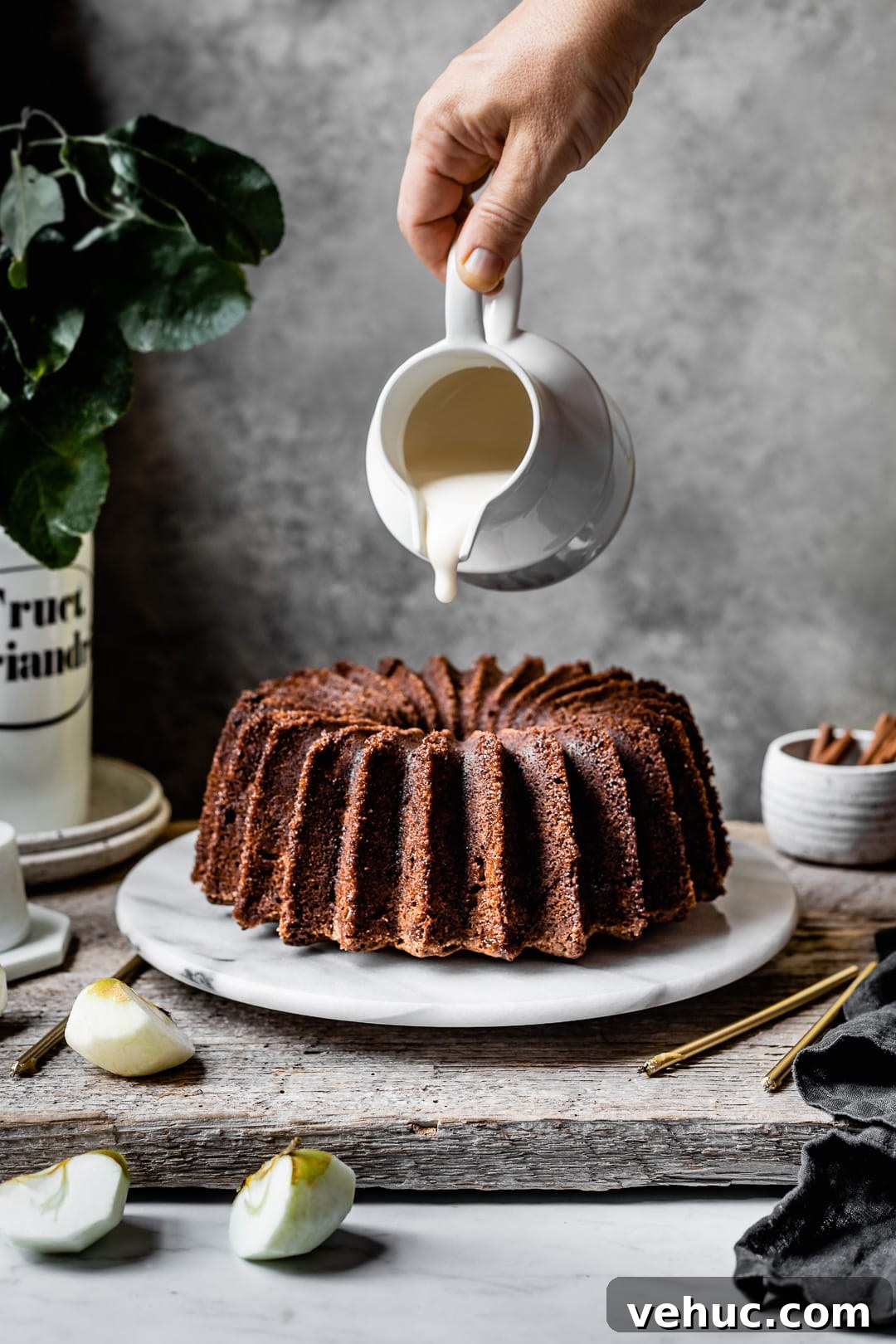 Moist Applesauce Bundt Cake Recipe for Fall Baking 4 Hand pouring white glaze onto an apple bundt cake