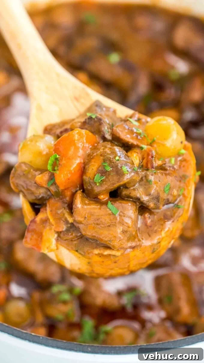 Classic Beef Bourguignon Recipe: Tender Braised Beef in Red Wine 4 Beef Bourguignon with juicy meat on a serving wooden spoon