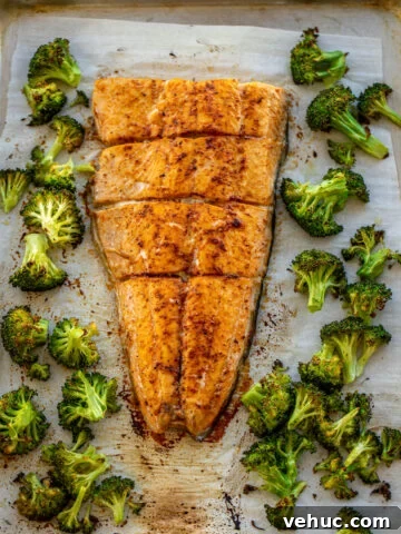 Large salmon fillet and roasted broccoli on a sheet pan
