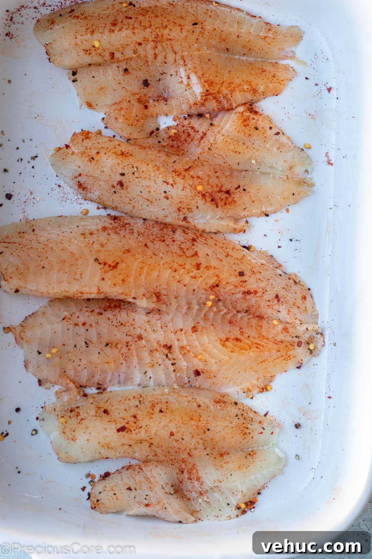 Garlic Butter Tilapia Recipe with Lemon and Herbs 5 Seasoned tilapia fillets in a bowl.