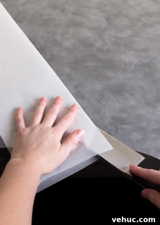 DIY Cake Strips: How to Wrap, Use, and Bake Even Layers 4 A large knife being used to split the baking paper in half lengthwise.