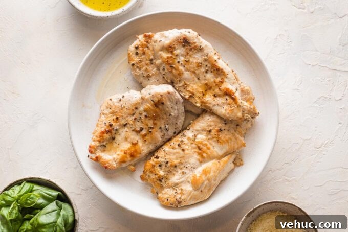 Pesto Chicken with Roasted Artichokes Recipe 4 Browned chicken breasts resting on a plate.