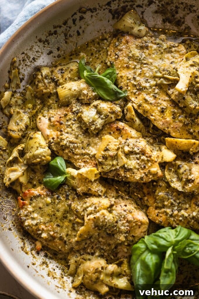 Pesto Chicken with Roasted Artichokes Recipe 9 Close-up of a tender chicken breast served with pesto cream sauce and artichoke hearts.