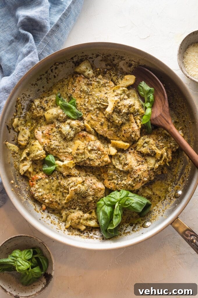 Pesto Chicken with Roasted Artichokes Recipe 10 Skillet with pesto artichoke chicken and a wooden spoon about to serve portions.