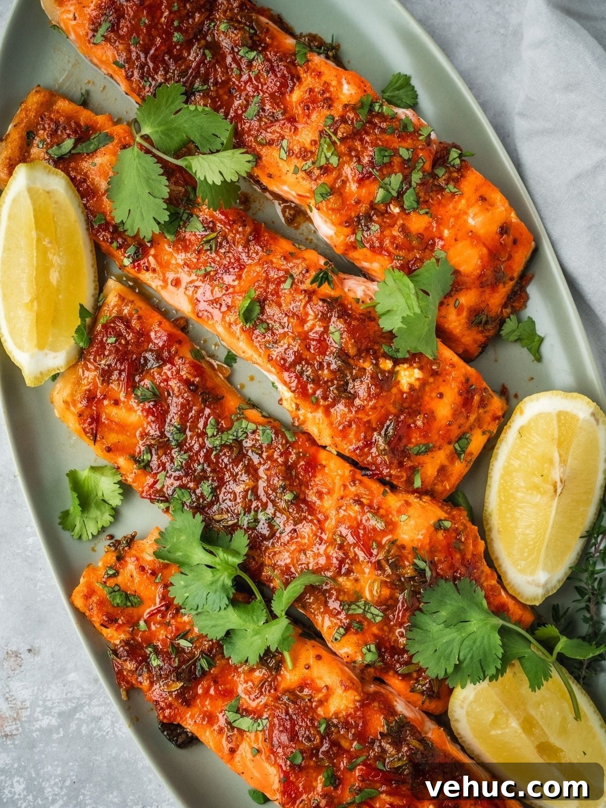 Honey Harissa Salmon with Garlic, Thyme & Lemon Roast 14 Honey Harissa Salmon fillets on a platter garnished with chopped cilantro and lemon wedges.