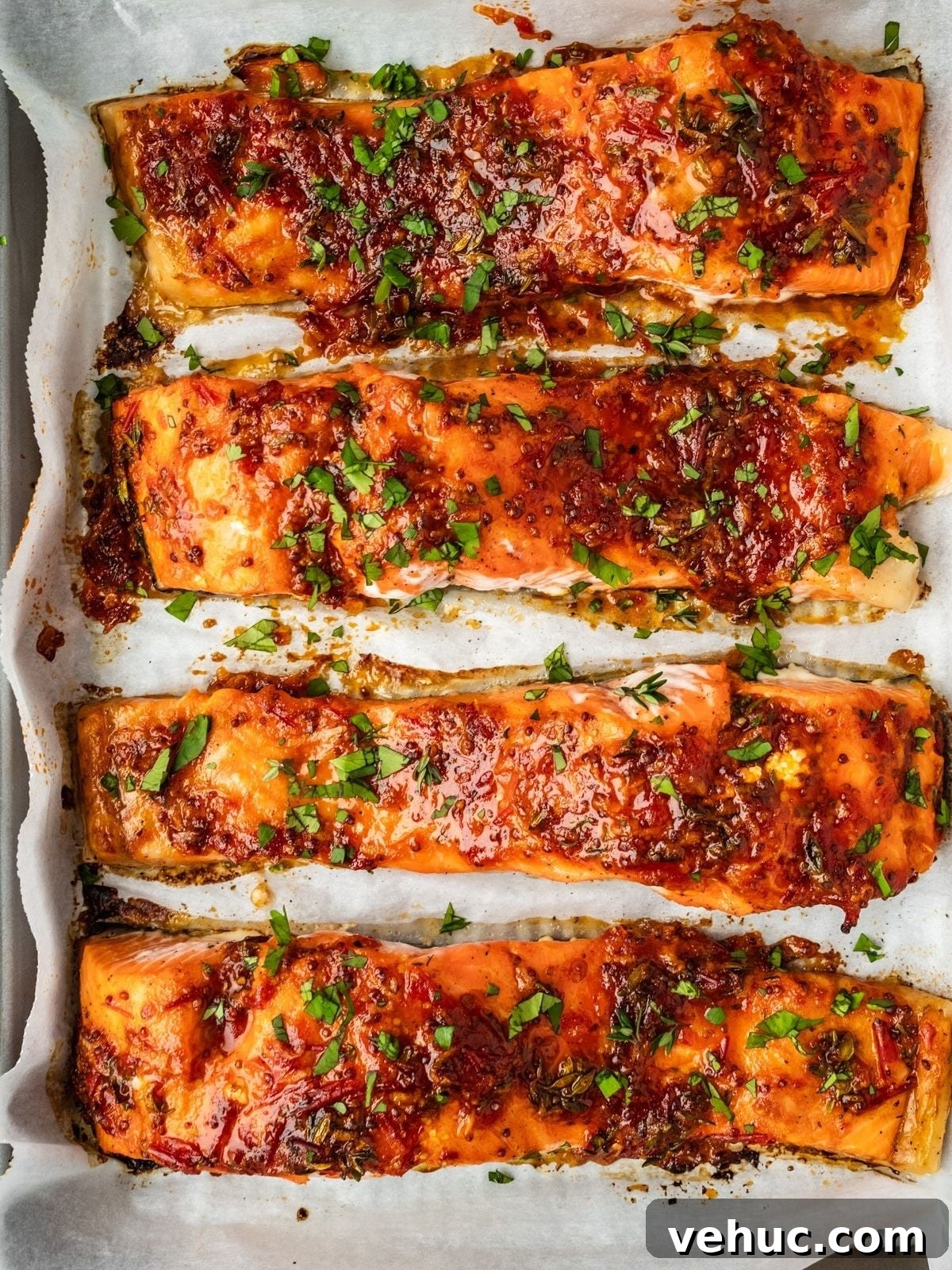 Honey Harissa Salmon with Garlic, Thyme & Lemon Roast 8 Baked salmon filets on a baking tray garnished with chopped cilantro.
