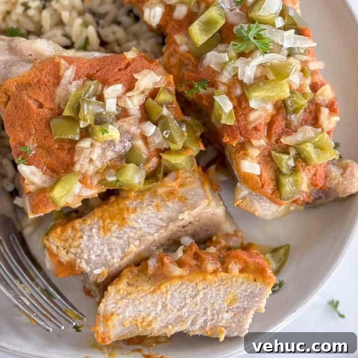 Glazed Teriyaki Pork Tenderloin Recipe with Garlic and Ginger 2 Close-up of tender smothered pork chop with a fork, topped with peppers and onions.