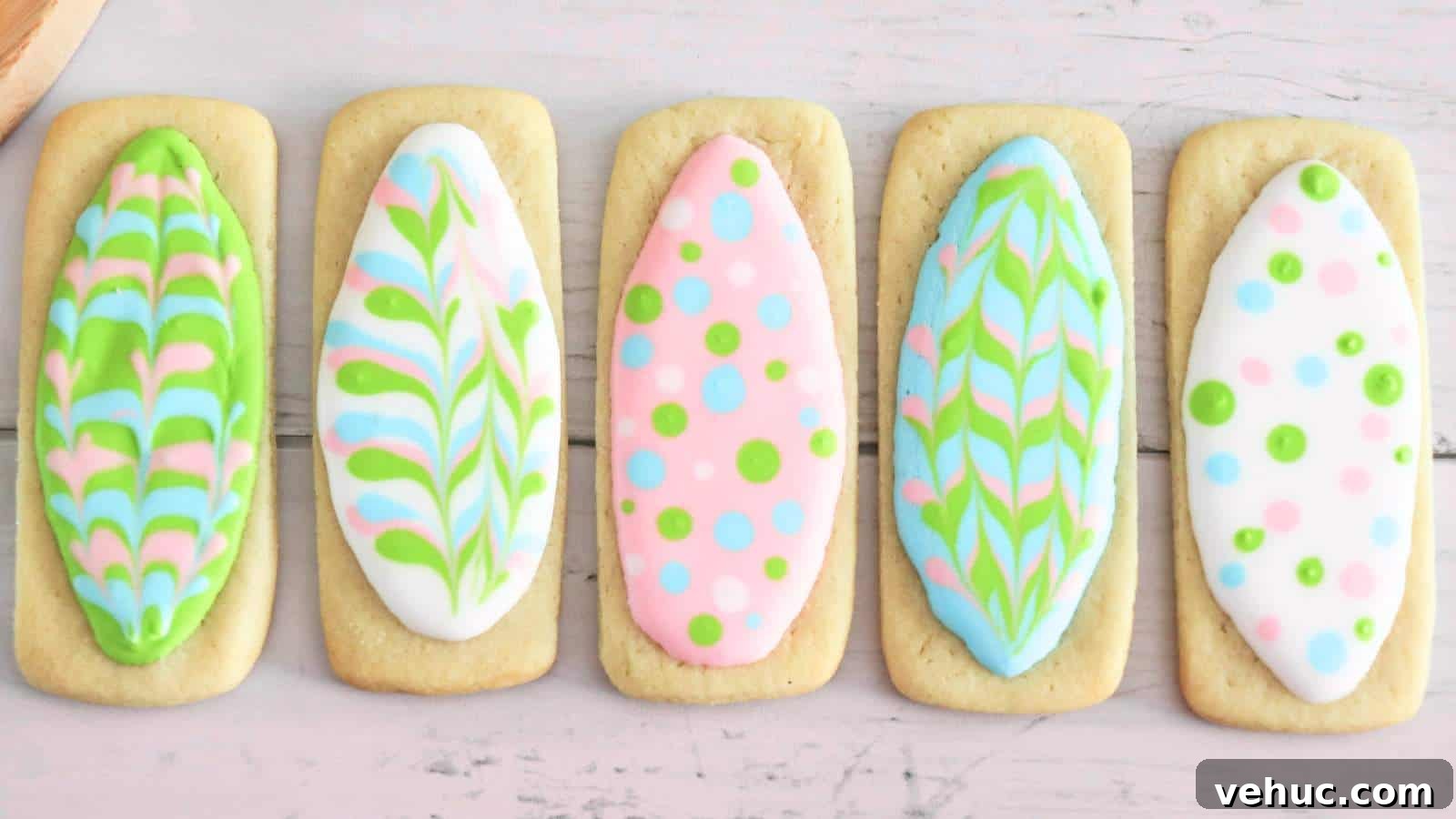 A row of easter egg-shaped cookies with colorful icing designs on a light wooden surface.